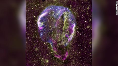 Se muestra una imagen de radio (púrpura), UV (amarillo) y rayos X (azul) del remanente de supernova del anillo Cygnus en la Vía Láctea. 