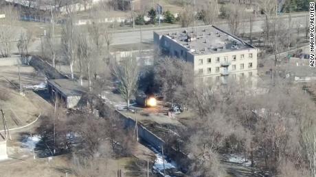 Esta captura de pantalla de un dron muestra un vehículo militar disparando cerca de un edificio.