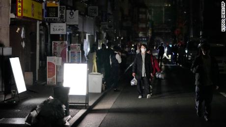 La gente camina por una calle durante un corte de energía en Tokio.