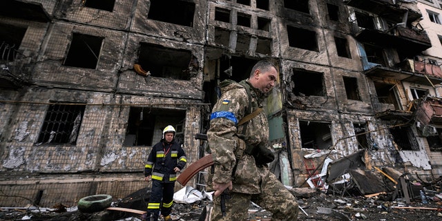 Soldados y bomberos ucranianos registran un edificio destruido después de un ataque con bomba en Kiev, Ucrania, el lunes 14 de marzo de 2022 (AP Photo/Vadim Ghirda)