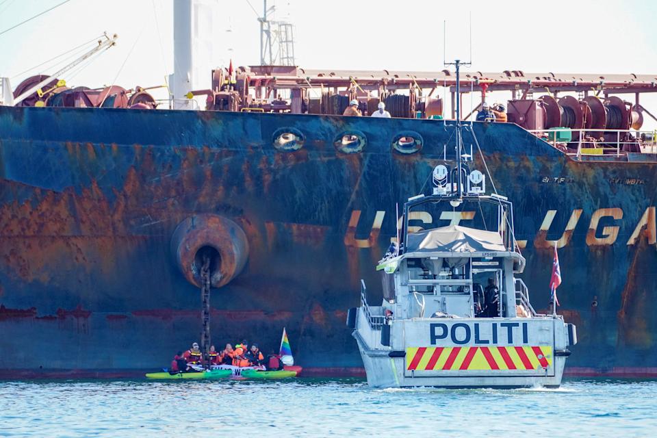 Un barco policial navega cerca de miembros de la organización Greenpeace que intercepta un petrolero 