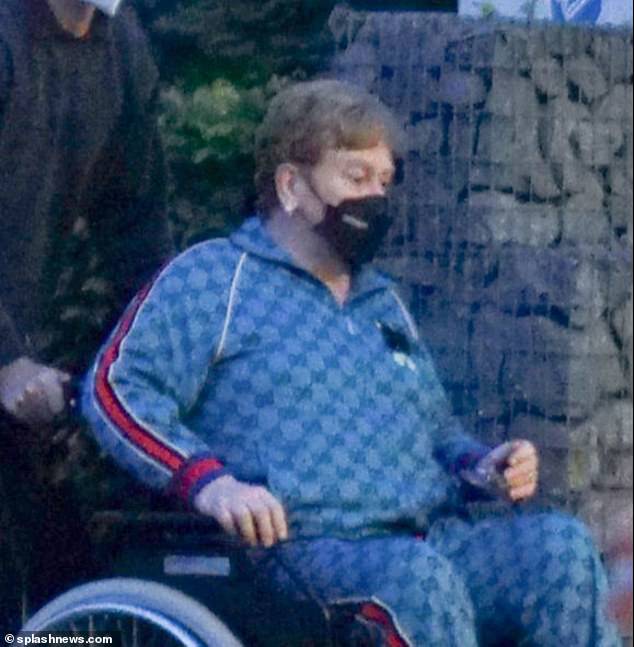 Aspecto extremo: Elton John, de 75 años, fue fotografiado siendo empujado a una silla de ruedas en el aeropuerto de Leipzig el viernes antes de su actuación en el Jubileo después de tomar un descanso debido a sus problemas.