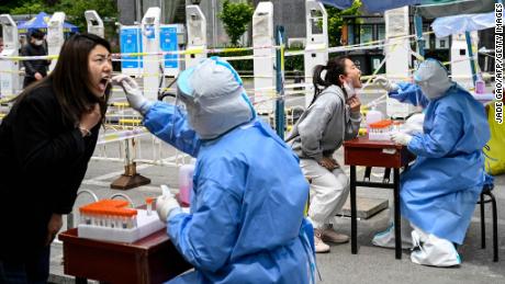 Los trabajadores de la salud toman muestras de hisopos para analizar el covid-19 en un sitio de prueba temporal a lo largo de una calle en Beijing el 11 de mayo de 2022.