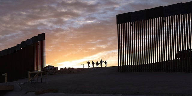 ARCHIVO - Familias inmigrantes de Brasil pasan por un hueco en el muro fronterizo para llegar a Estados Unidos después de cruzar de México a Yuma, Arizona, para buscar asilo.