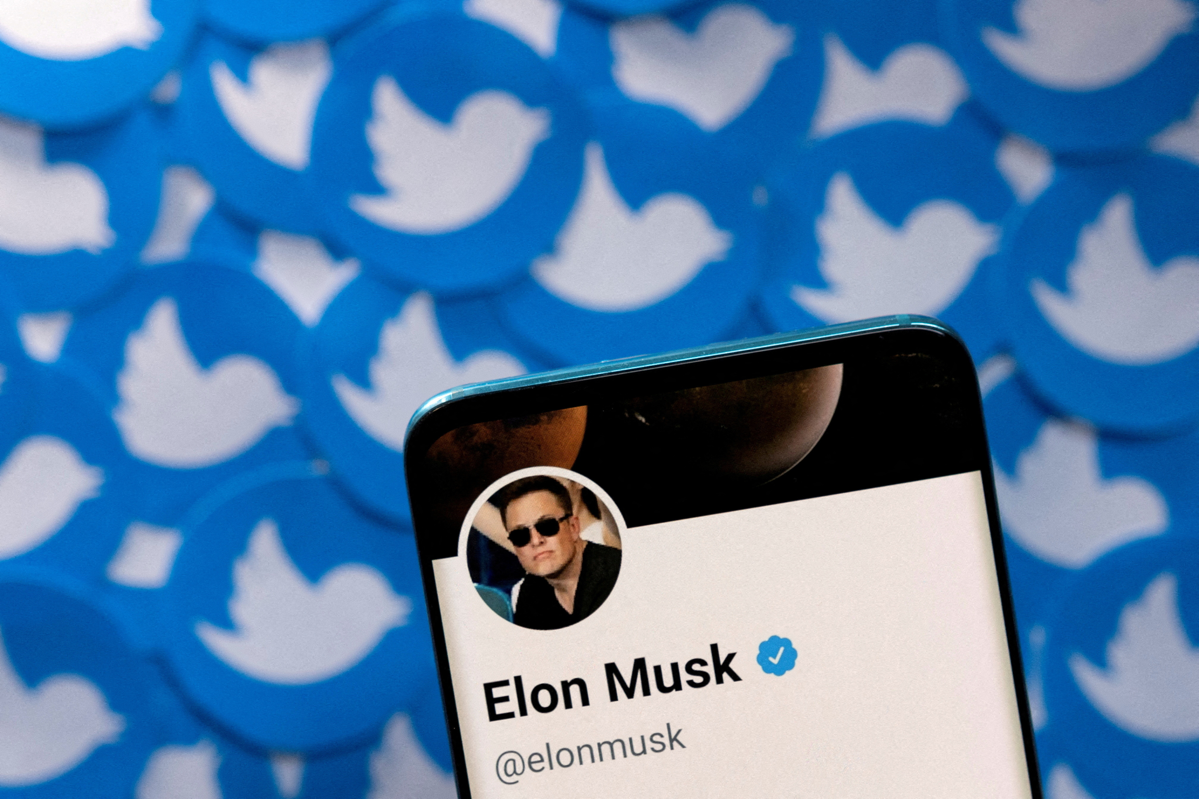 La ilustración muestra el perfil de Twitter de Elon Musk en un teléfono inteligente y los logotipos de Twitter impresos.